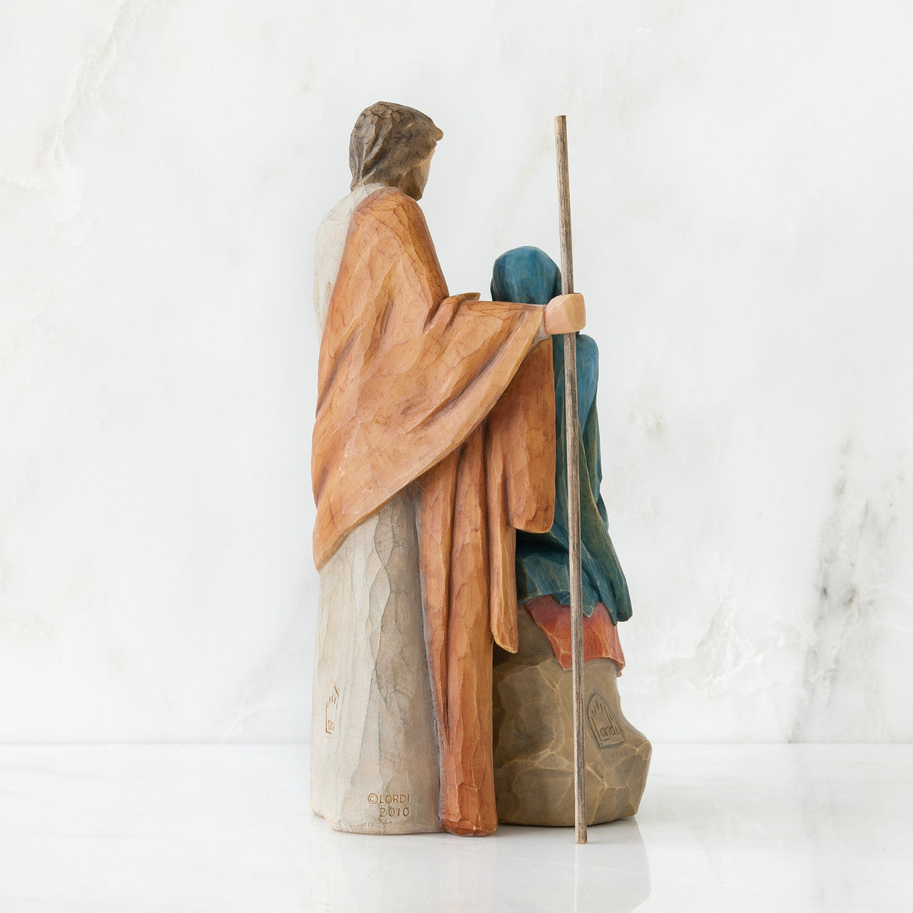 Wooden nativity scene figurine of a shepherd with a lamb on a white background