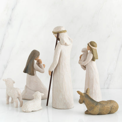 A set of hand-painted resin nativity figures, including figures of Joseph, Mary, a shepherd, a donkey, and two sheep, placed on a marble surface.