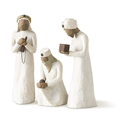 A set of three hand-painted wooden nativity figures depicting the three wise men, in a kneeling position, with a focus on the figure in the foreground holding a block.